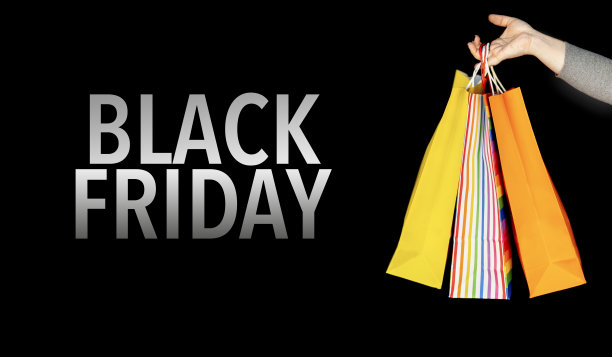 黑色星期五的商业活动。特写一个女人的手拿着彩色的购物袋在黑色背景。购物的概念图片下载