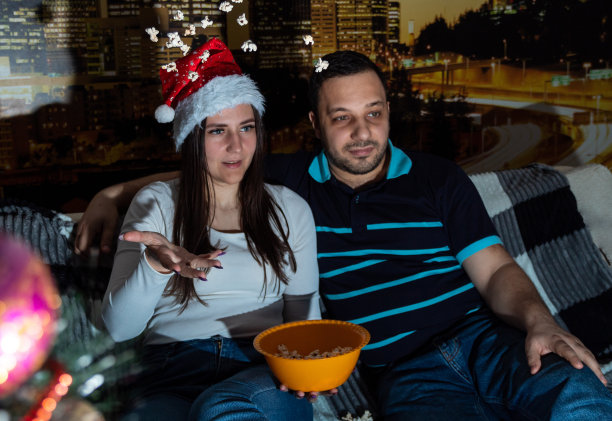 夫妻在看电影，女人在撒爆米花。有选择性的重点。关于家庭、休闲的网站图片。图片下载