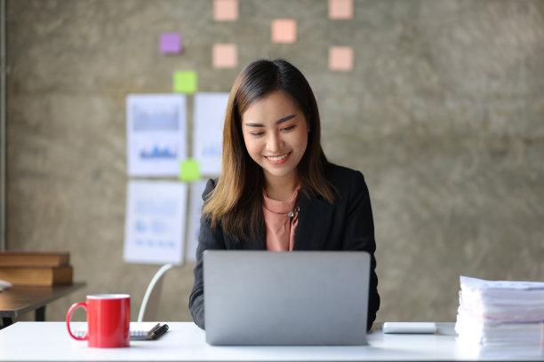 迷人的年轻亚洲商业女性在办公室用笔记本电脑工作。图片下载