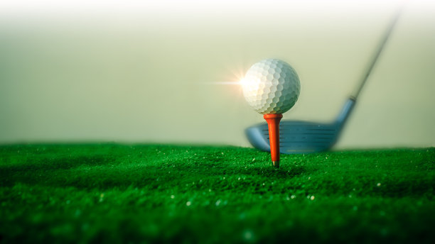 高尔夫球在击球平台上的特写高尔夫球在绿色草地上的红色平台上，高尔夫球杆在后面准备击球。这是世界各地的人们在节日期间为健康和商业交易而进行的运动。运动与健康概念图片下载