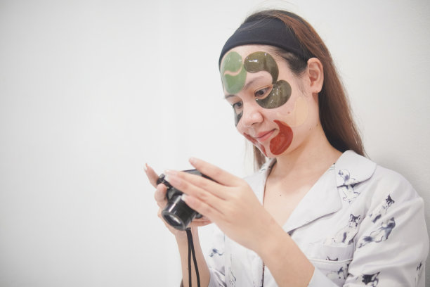 戴着化妆面具的亚洲女性正在用数码相机看照片。图片下载