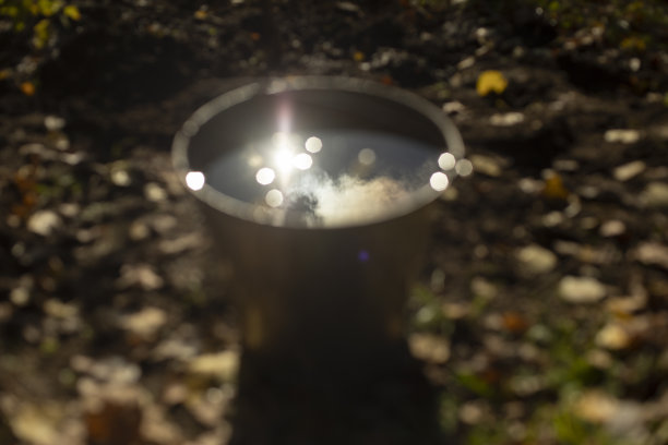 桶里的水。花园里的钢桶。灌溉植物时太阳在水中的反射。图片下载