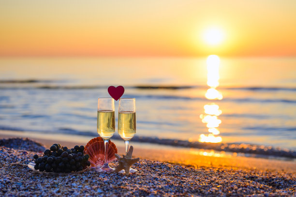 浪漫的日落。为沙滩上热恋中的情侣送上几杯葡萄酒。图片下载