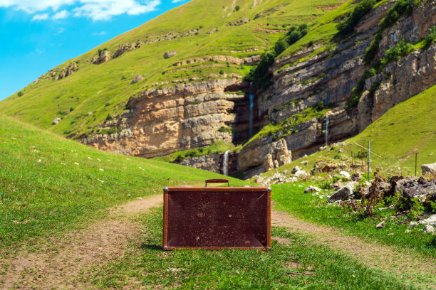 破旧的皮箱在山区的土路上图片下载