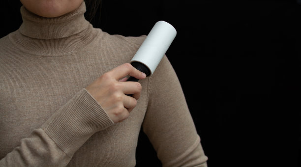 一名妇女用粘性滚筒清洗她的毛衣上的羊毛。图片下载