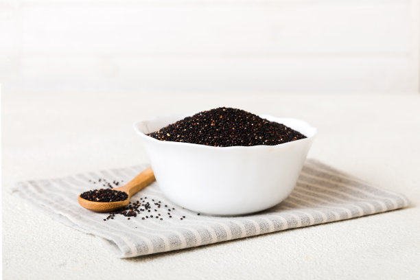 在碗和勺子里的藜麦种子在彩色背景上。健康的kinwa在小碗里。健康的超级食物图片下载