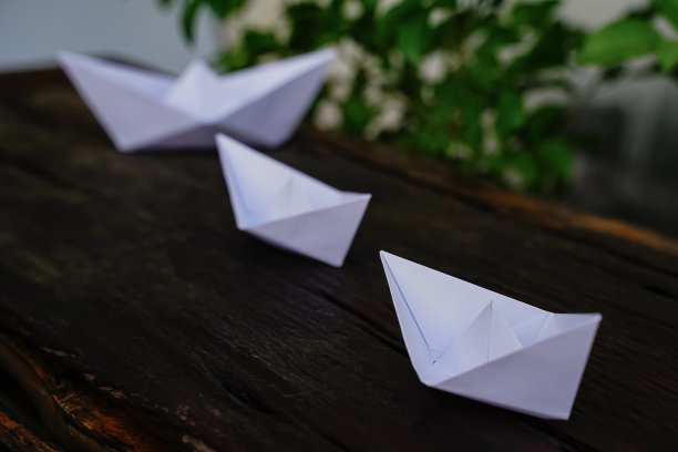 折纸，白色的纸船孤立在木地板上。纸船意味着步行。自由感领导图片下载