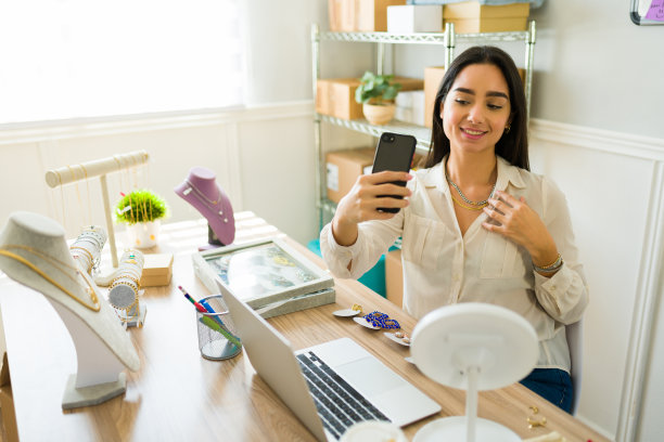 快乐的年轻女子试穿她网上商店的项链图片下载