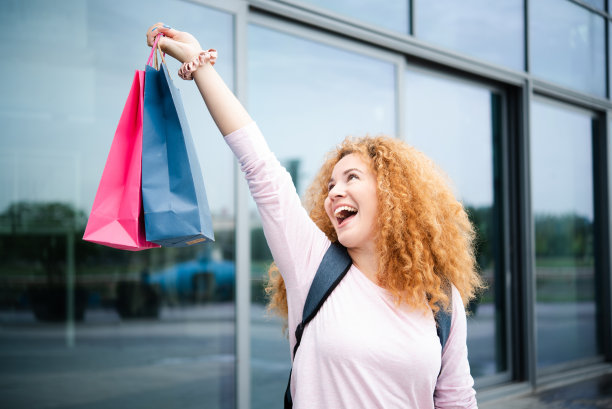 一个兴奋的女孩在购物后举起购物袋的画像图片下载