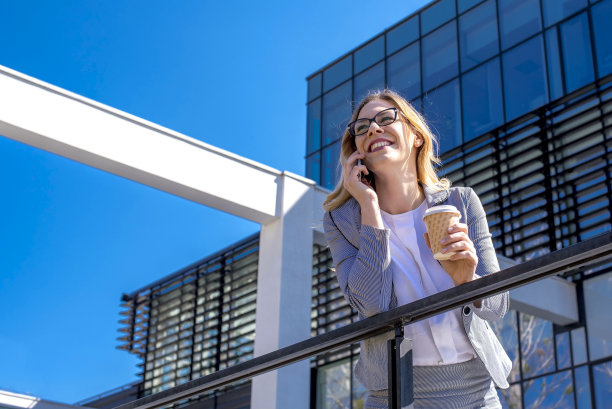 一位女商人在办公楼前打电话图片下载