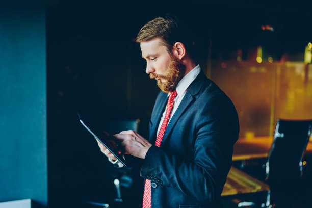 自信的男性企业家站在办公室用平板电脑查看通知，骄傲的ceo穿着西装使用平板电脑和无线网络浏览信息丰富的行业新闻图片下载