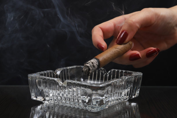 烟灰缸上，一个女人手里拿着点燃的雪茄图片下载