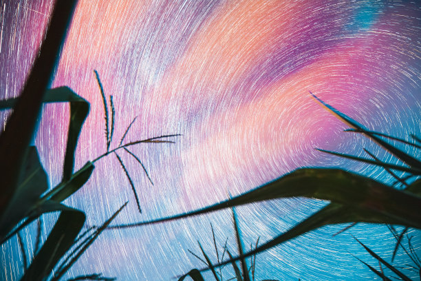 明亮的夜晚星空发光的星星和流星轨迹在玉米田。平静,冷静。柔和的蓝橙粉颜色。自然母亲的力量概念。幻想，幻觉，梦幻。天空中恒星的旋转图片下载