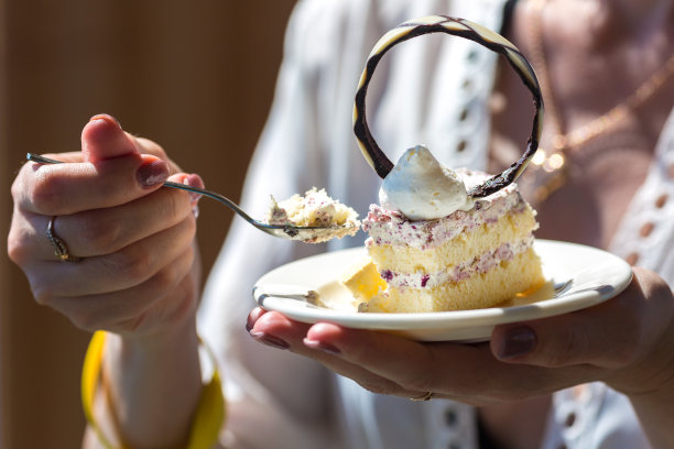 在大海的背景下，女性手中盛着甜点的盘子图片下载
