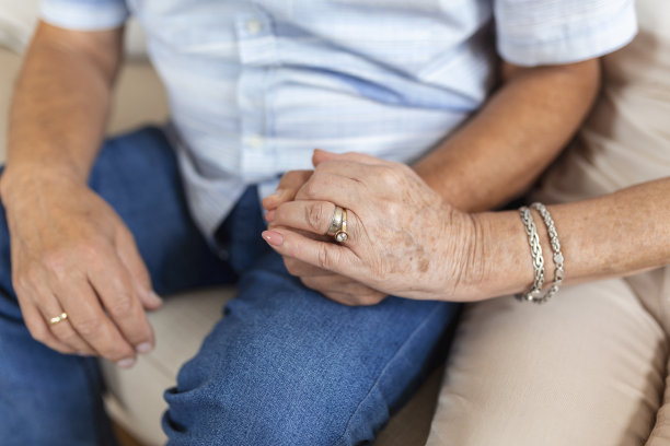 特写的成熟老夫老妻手牵着手表示爱和关怀。老夫妇手牵着手坐在一起。老年人关系，婚姻观念图片下载