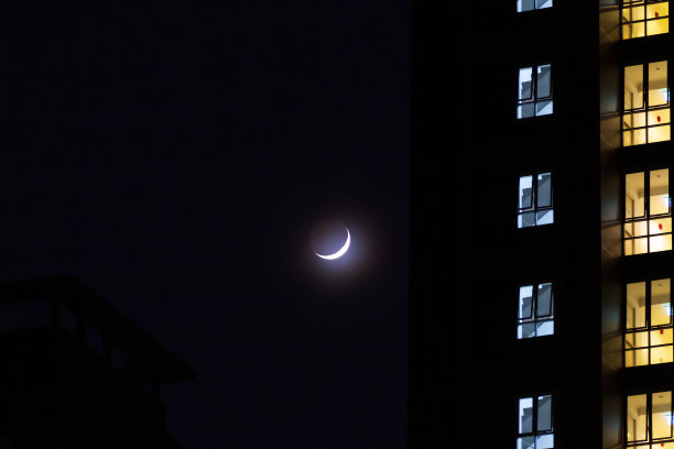 美丽的午夜城，有一轮新月和大地的光芒是一种柔和。城里的夜间模式。图片下载