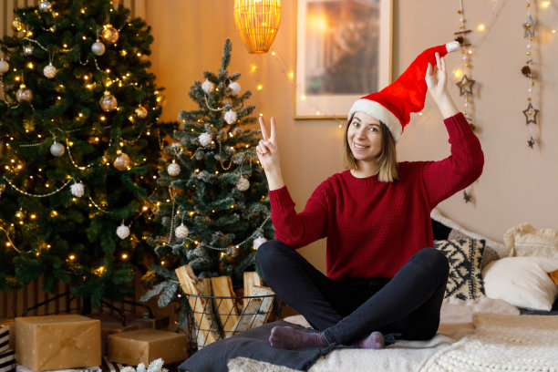 一个女人坐在为圣诞节装饰的房间的床上图片下载