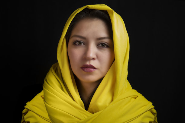 一个美丽的白种人妇女，头上戴着围巾，与黑色背景隔离开来图片下载