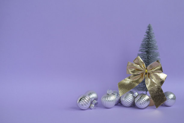 圣诞树，金色的蝴蝶结和紫色背景上的银球。圣诞节的背景。图片下载