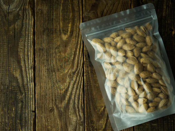 没有去皮的杏仁装在有拉链的包装里。孤立的木制背景与修剪路径。图片下载