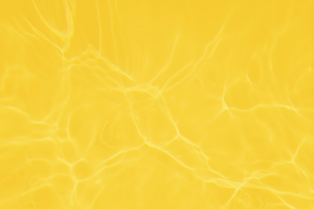 离焦模糊透明黄色颜色清澈平静的水面纹理与飞溅和气泡。新潮抽象的自然背景。阳光下的水波与复制空间。黄色水彩闪闪发光图片下载