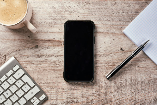 木桌，配有智能手机、键盘、一杯咖啡和一本笔记本。图片下载