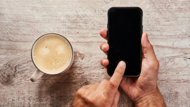 木桌，配有智能手机、键盘、一杯咖啡和一本笔记本。图片下载