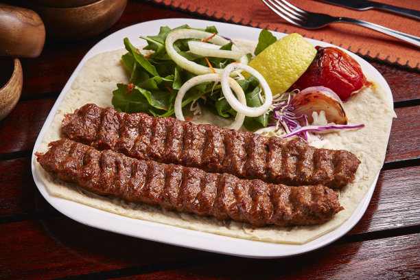 辣味烧烤唐杜里羊肉卡巴与面包，酸橙和沙拉在菜肴孤立的餐桌边的中东食物图片下载