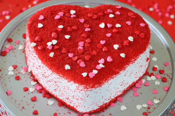 情人节蛋糕架上的整个红色天鹅绒蛋糕，脱水覆盆子粉，糖洒心，红色背景，高架视图图片下载