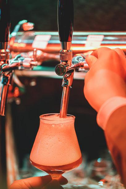 将自制精酿啤酒机中的啤酒倒入玻璃杯中图片下载