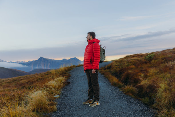 一个背着双肩包的男人在挪威的山上思考日落徒步旅行的侧视图图片下载