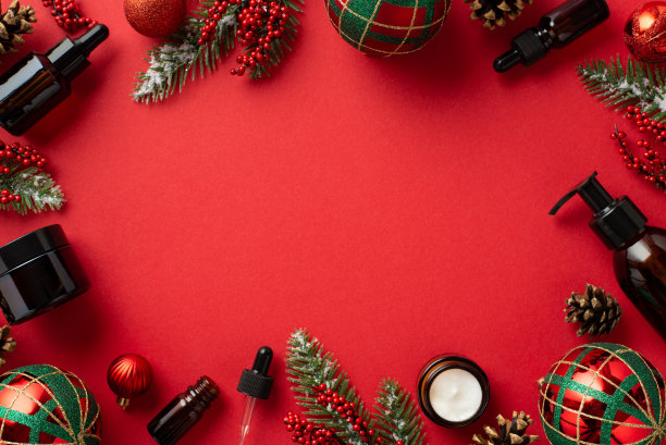冬季护肤理念。圣诞装饰的俯视图照片红色和绿色的装饰物琥珀玻璃瓶槲寄生浆果松果冷杉枝孤立的红色背景与中间的空白图片下载