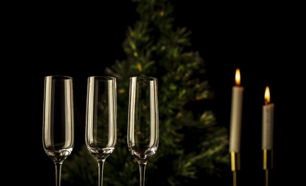 三个香槟杯，黑色背景下有圣诞树和闪电蜡烛图片下载