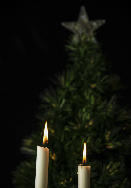 白色的蜡烛和黑色背景下的圣诞树图片下载