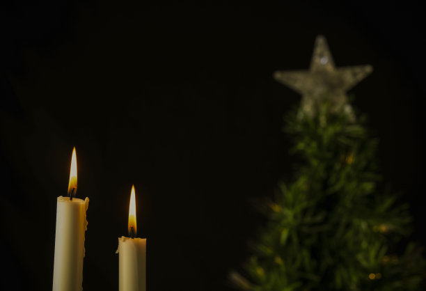 白色的蜡烛和黑色背景下的圣诞树图片下载