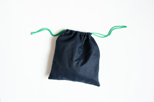 一个蓝色的织物袋与弦躺在一个白色的背景接近图片下载