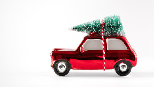 红色的玩具车上载着白色的圣诞树。图片下载