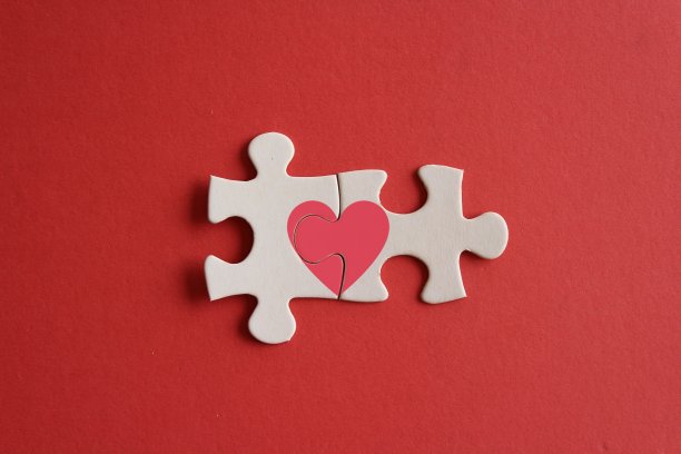 顶视图图像连接的拼图碎片与红色的心形图标在红色的背景。图片下载