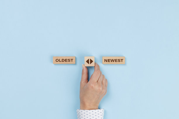 女性手拿着一个木制立方体，在最古老或最新的选项之间有箭头图标图片下载