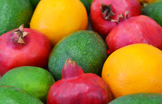 各种新鲜成熟的热带水果作为背景。鳄梨、橙子、酸橙和石榴。异域水果，纯素食品或饮食概念。图片下载