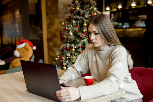 年轻漂亮的女人在café为圣诞节工作图片下载