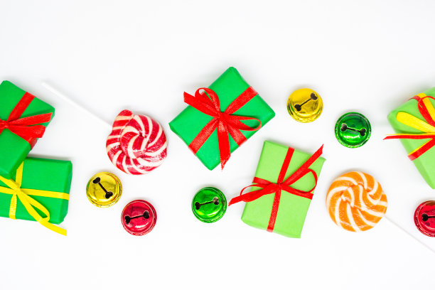 节日快乐:礼物有棒棒糖和白色背景的红、绿、金铃铛，复制空间。圣诞节，促销，儿童派对的概念图片下载