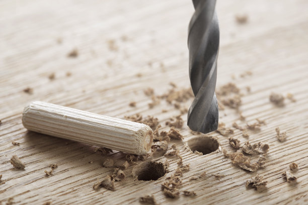 钻头在橡木木板上钻孔，用于木销钉。图片下载