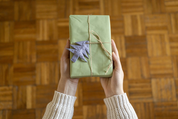 第一人称顶视图的妇女手拿工艺纸礼品盒在木桌上图片下载