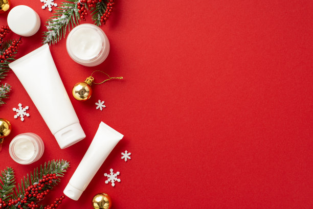 冬季护肤理念。俯视图照片白色化妆品瓶松枝在霜金色的小饰物槲寄生浆果和雪花孤立的红色背景与copyspace图片下载