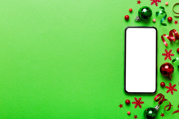 圣诞节网上购物从家里的电话与空白白色显示顶视图。智能手机与复制空间彩色背景与圣诞装饰球，。寒假销售背景图片下载