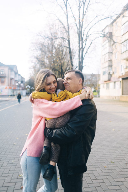 父母亲吻儿子的脸颊。漫步在公园和秋天的街道。不同的父母。快乐的童年。关怀的家庭和幸福的脸庞图片下载