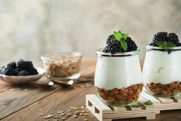 酸奶配格兰诺拉麦片，黑莓浆果水果和什锦麦片，装在木制背景的玻璃罐中。健康早餐的概念。健康的早餐，俯视图图片下载