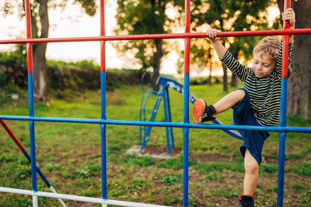 那男孩在儿童游乐场上爬单杠玩得很开心图片下载