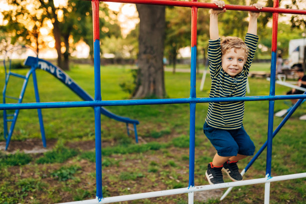 一个可爱的小男孩在外面的操场上玩攀爬架图片下载